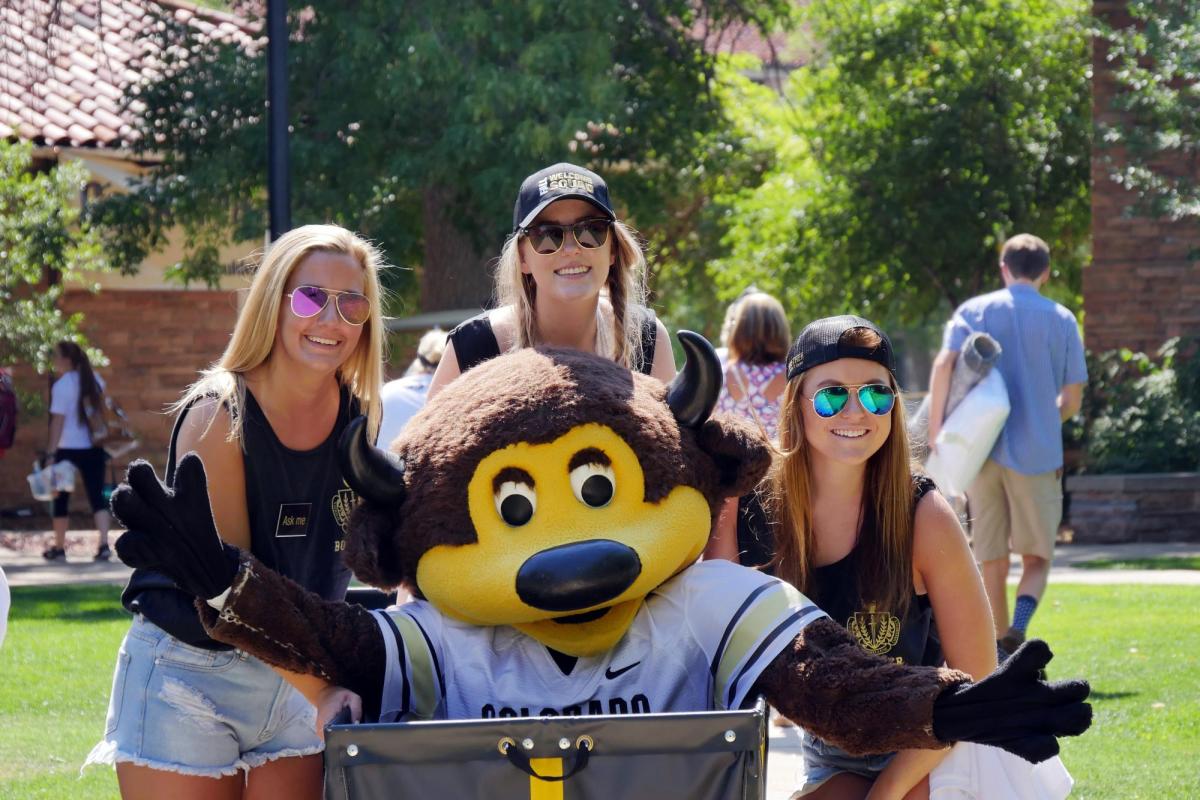 Three students strike a pose with Chip.