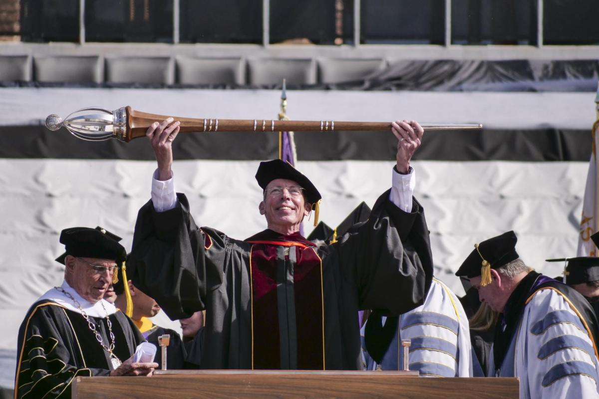 Bud Coleman lifts the ceremonial mace as part of commencement