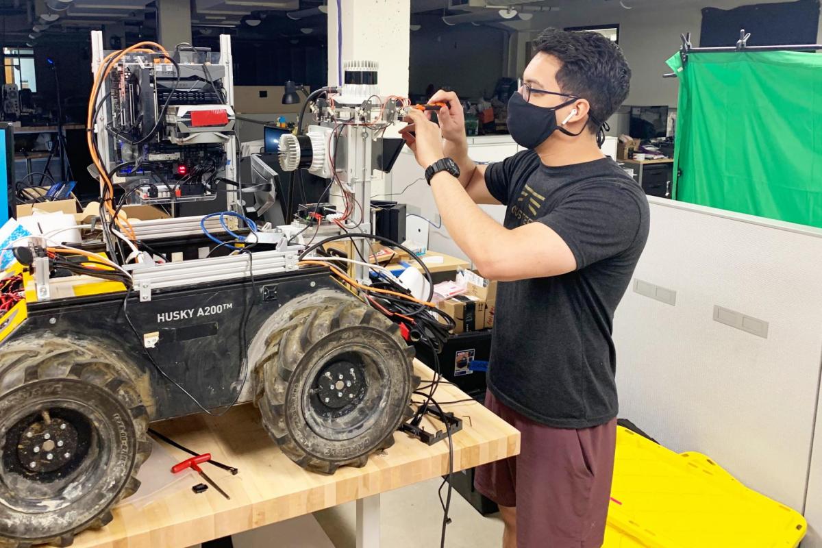 A member of a robotics research team working in a lab after a return to on-campus research