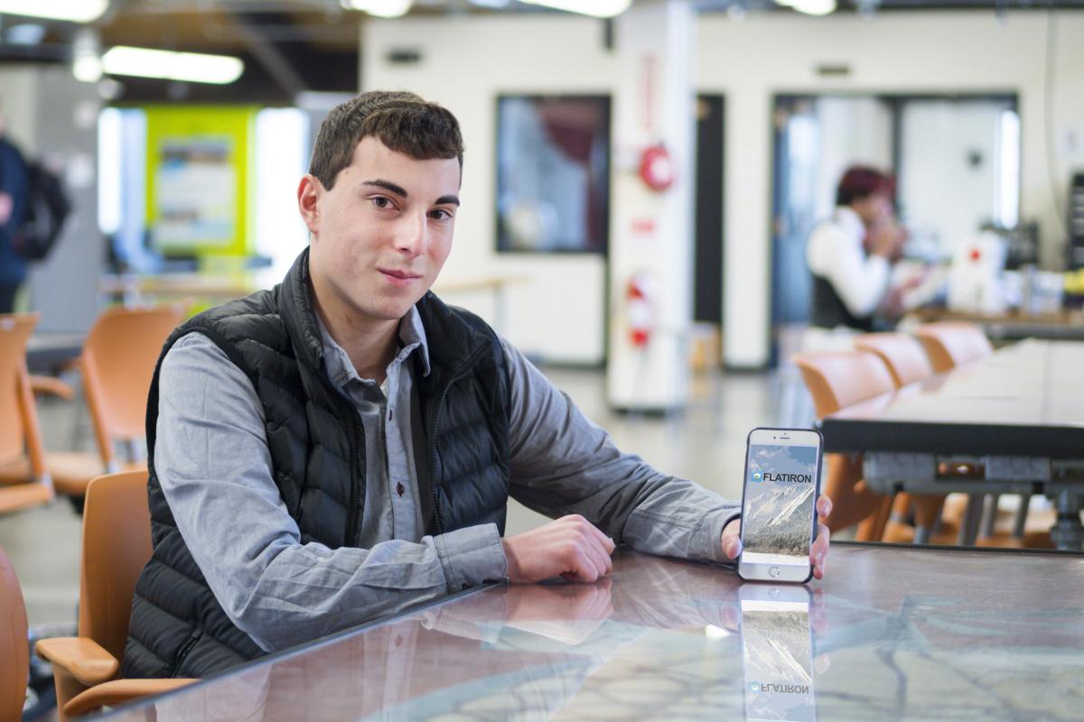 David Meyer holds his phone to display the Flatiron Chat app on screen