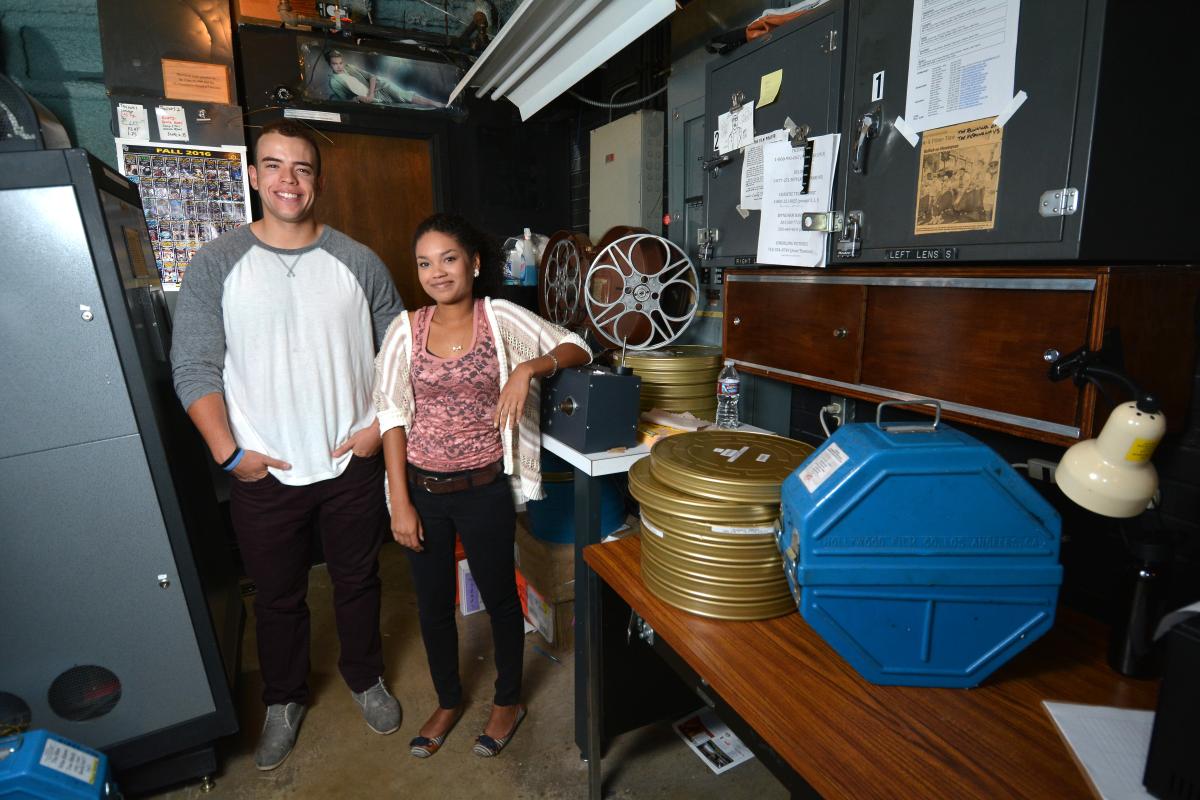 Adam Elbeck and Melina Dabney pose in the CU Boulder film lab with stacks of movie reels