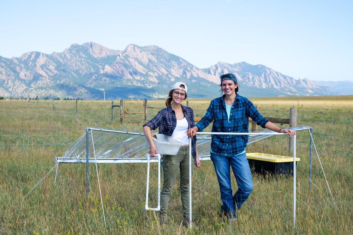 Graduate student Julie Larson and undergraduate Emily Koke in grass