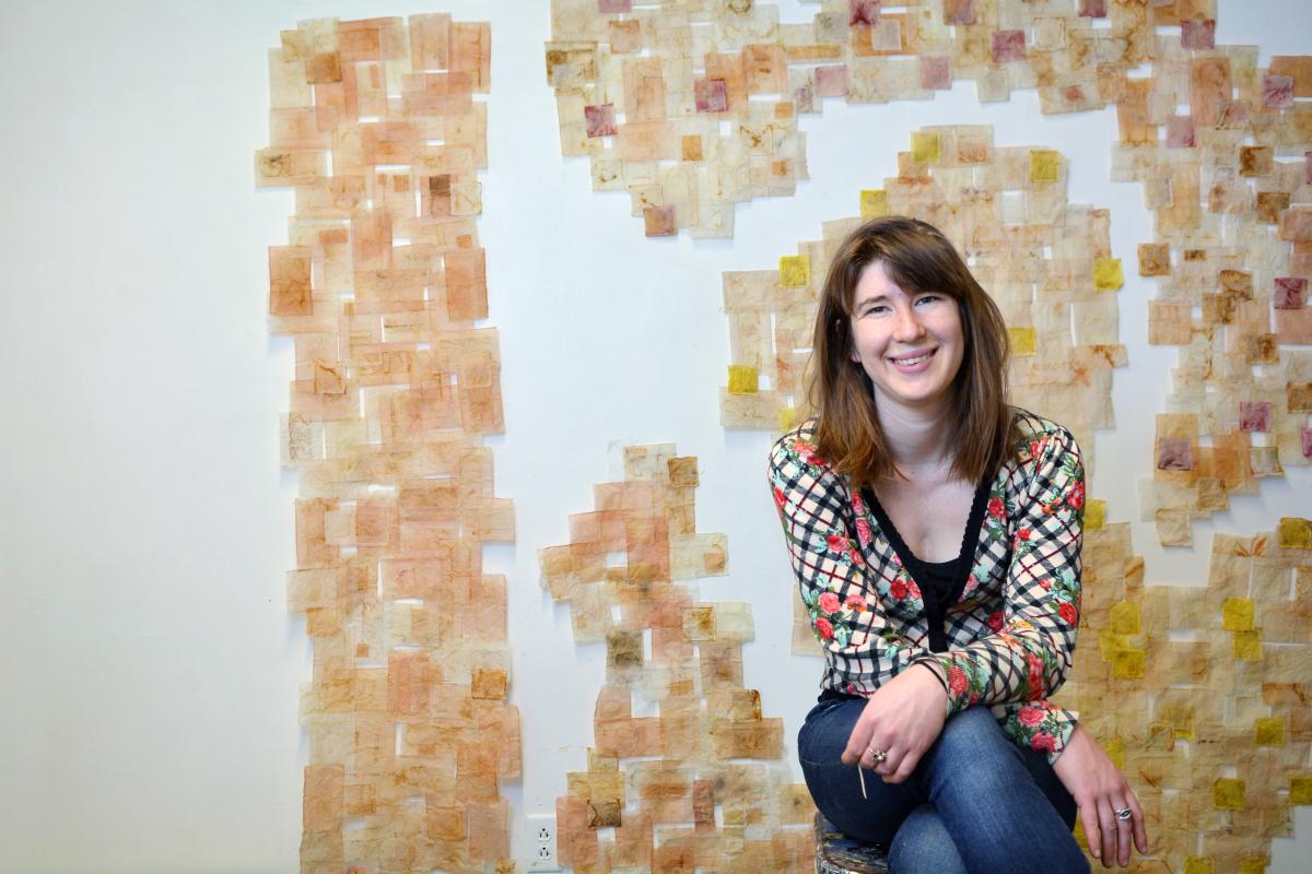 Ariana Kolins sits in front of a wall covered in used, empty tea bags