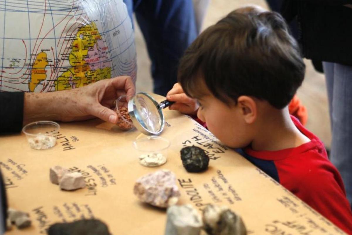 Kid looking at rocks through a magnifying glass