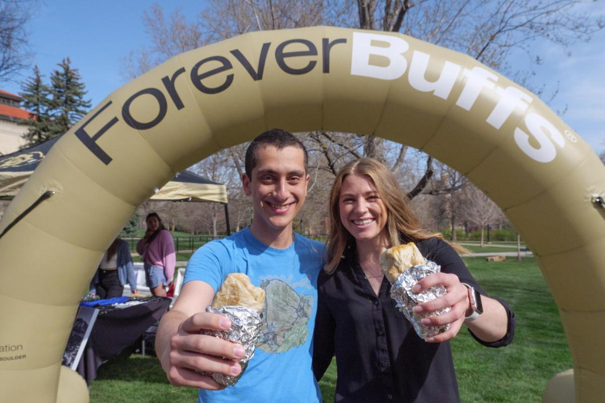 Two graduating students pose with free burritos in front of a Forever Buffs arch