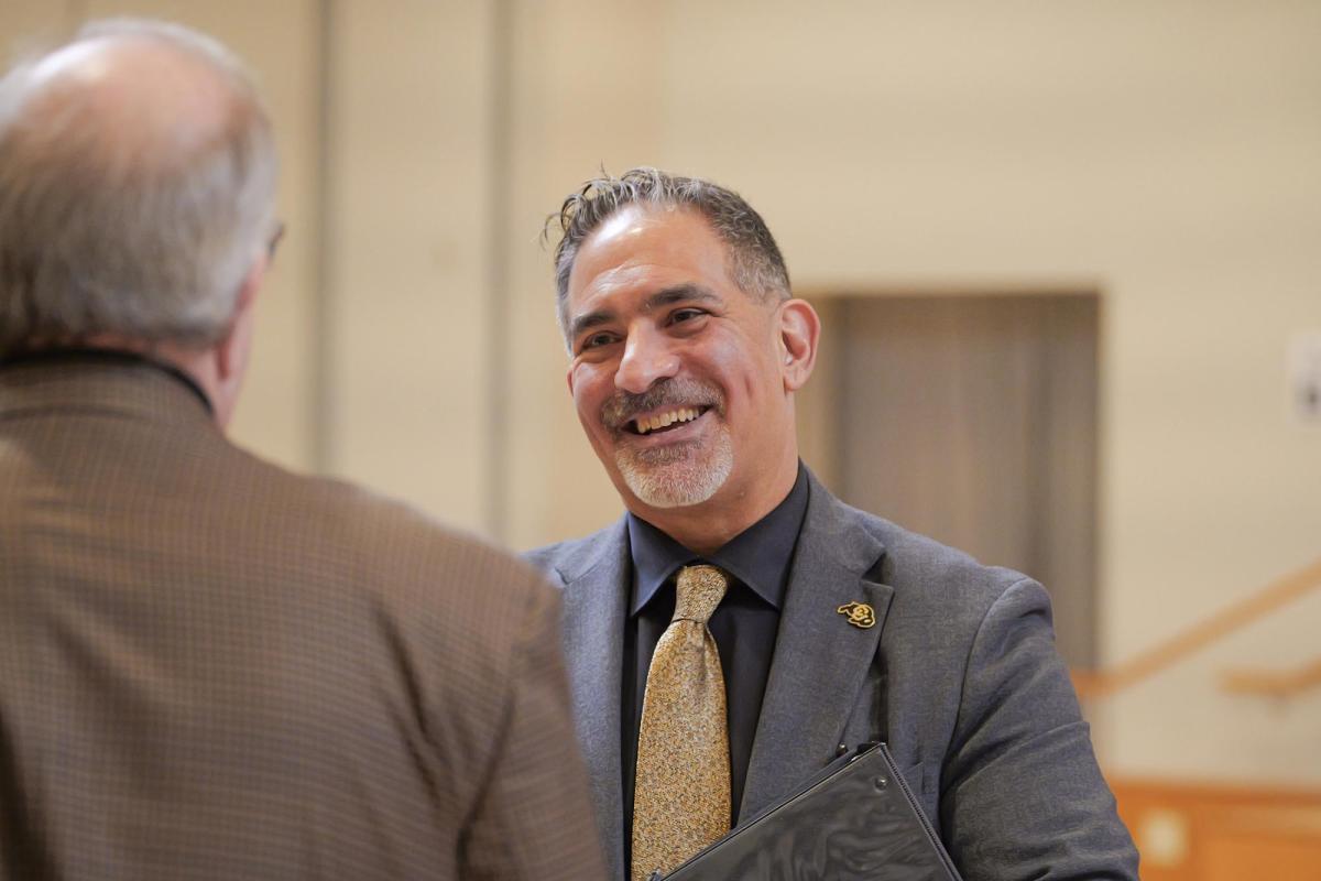 CU Boulder Chancellor Justin Schwartz interacts with a person standing before him.