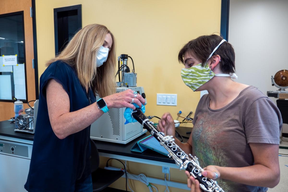 Graduate student Teyha Stockman, right, shows off her homemade bell cover made from medical mask material that helps decrease aerosol spread on her clarinet