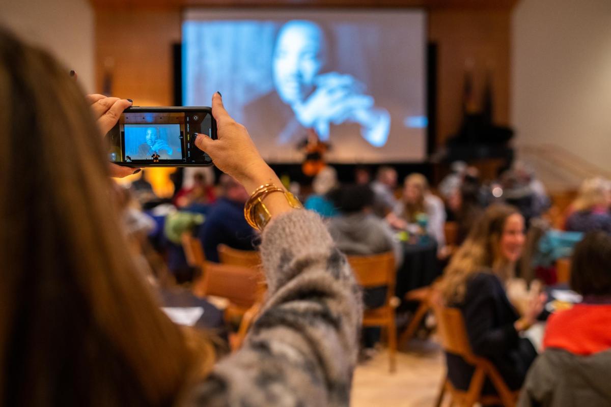 A person takes a photo of the projection at an MLK Day event on the CU Boulder campus.