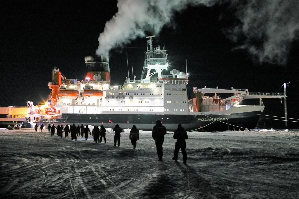 People walk across the ice toward Polarstern. Photo by Michael Gutsche.