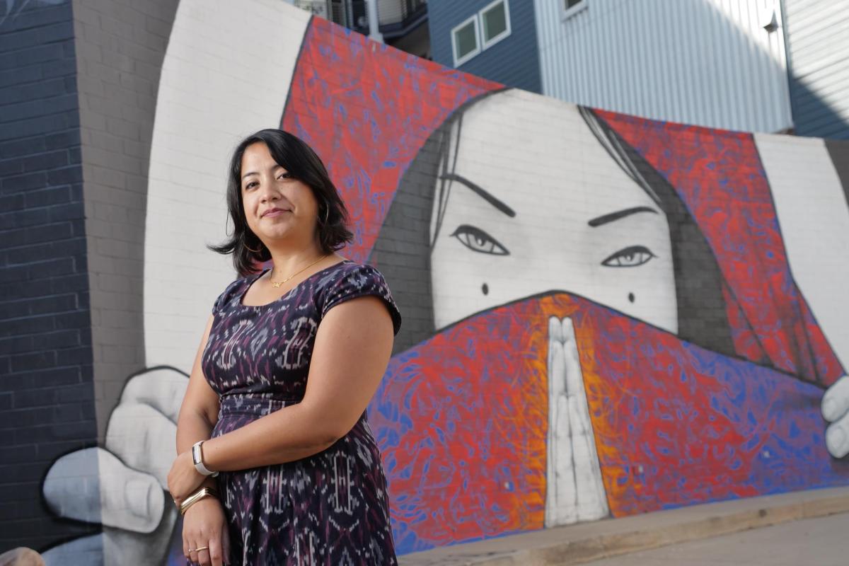 Noreen Naseem Rodriguez stands in front of a mural