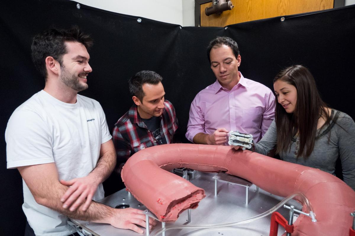 researchers with model of robotic small intestine