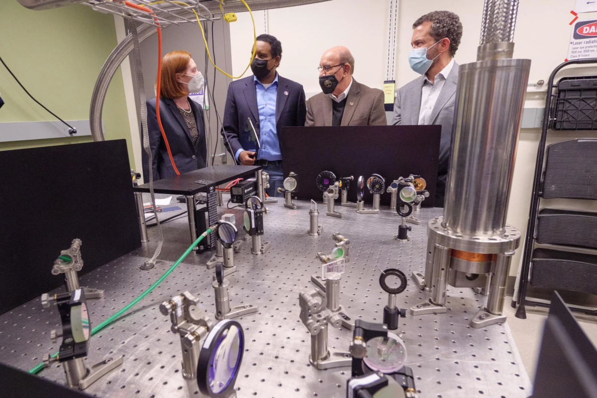 Margaret Murnane, U.S. Rep. Joe Neguse, Philip DiStefano and Todd Saliman inspect equipment in a lab