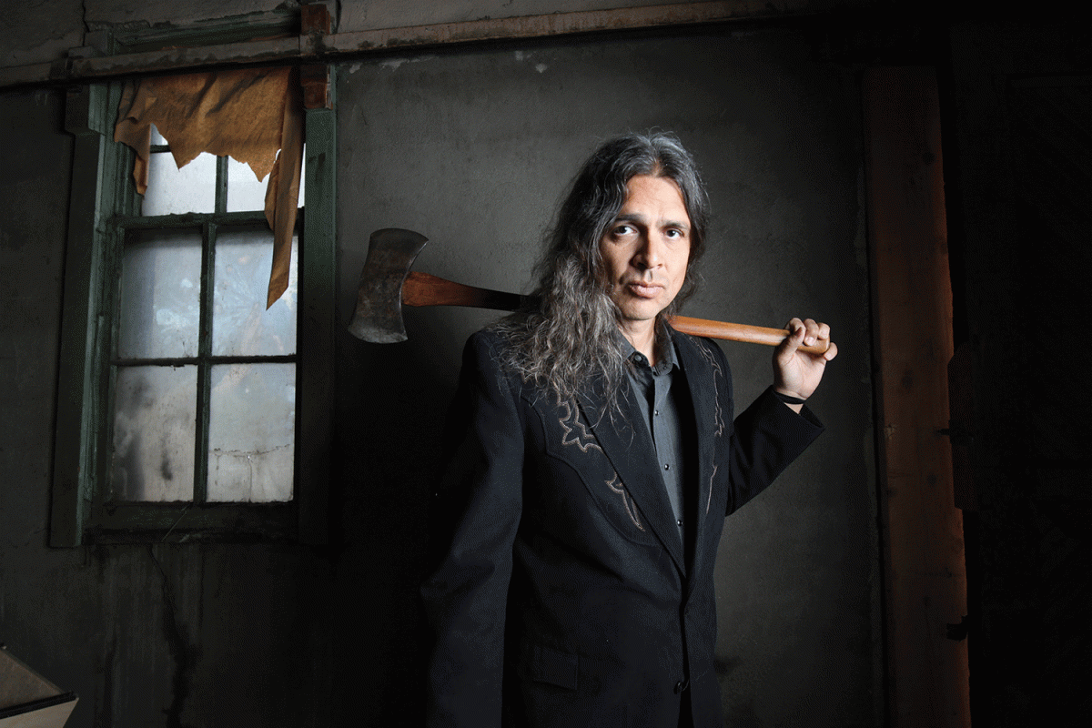 CU English Professor Stephen Graham Jones holds ax over shoulder