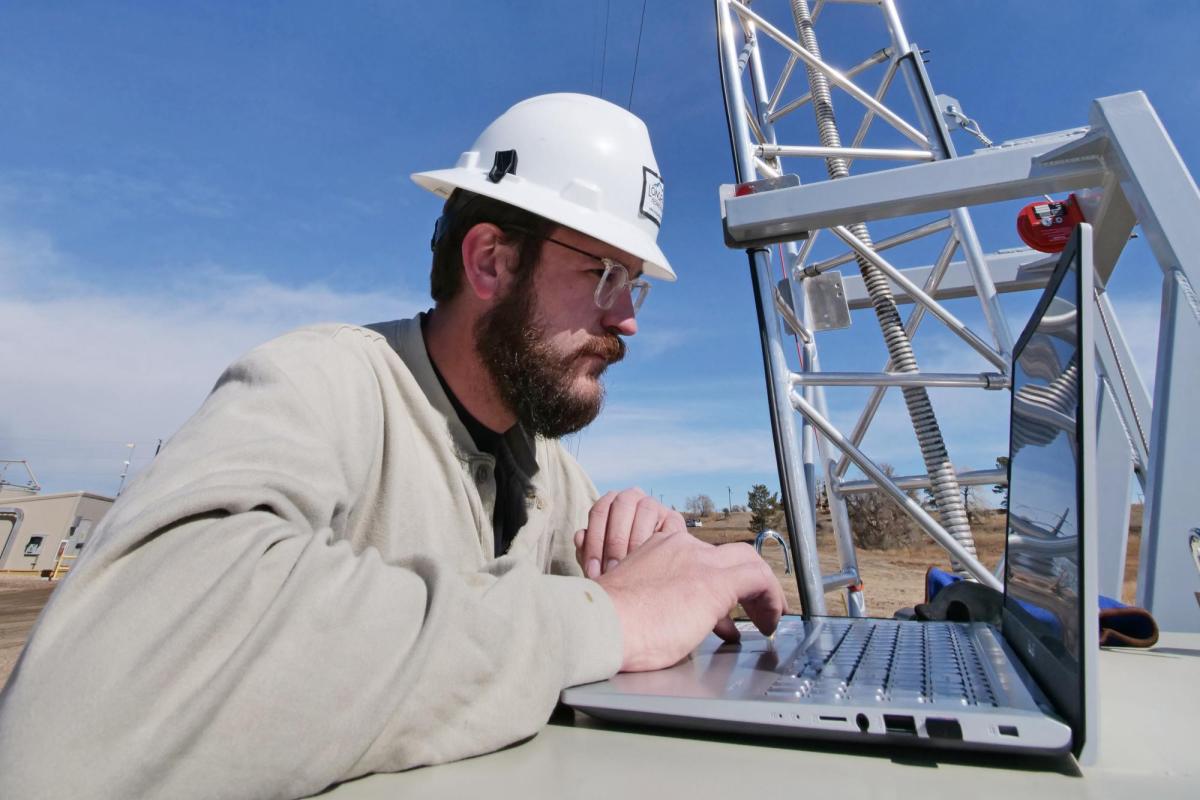 A technician inspects a high-tech laser on a tower in a natural gas site in Colorado