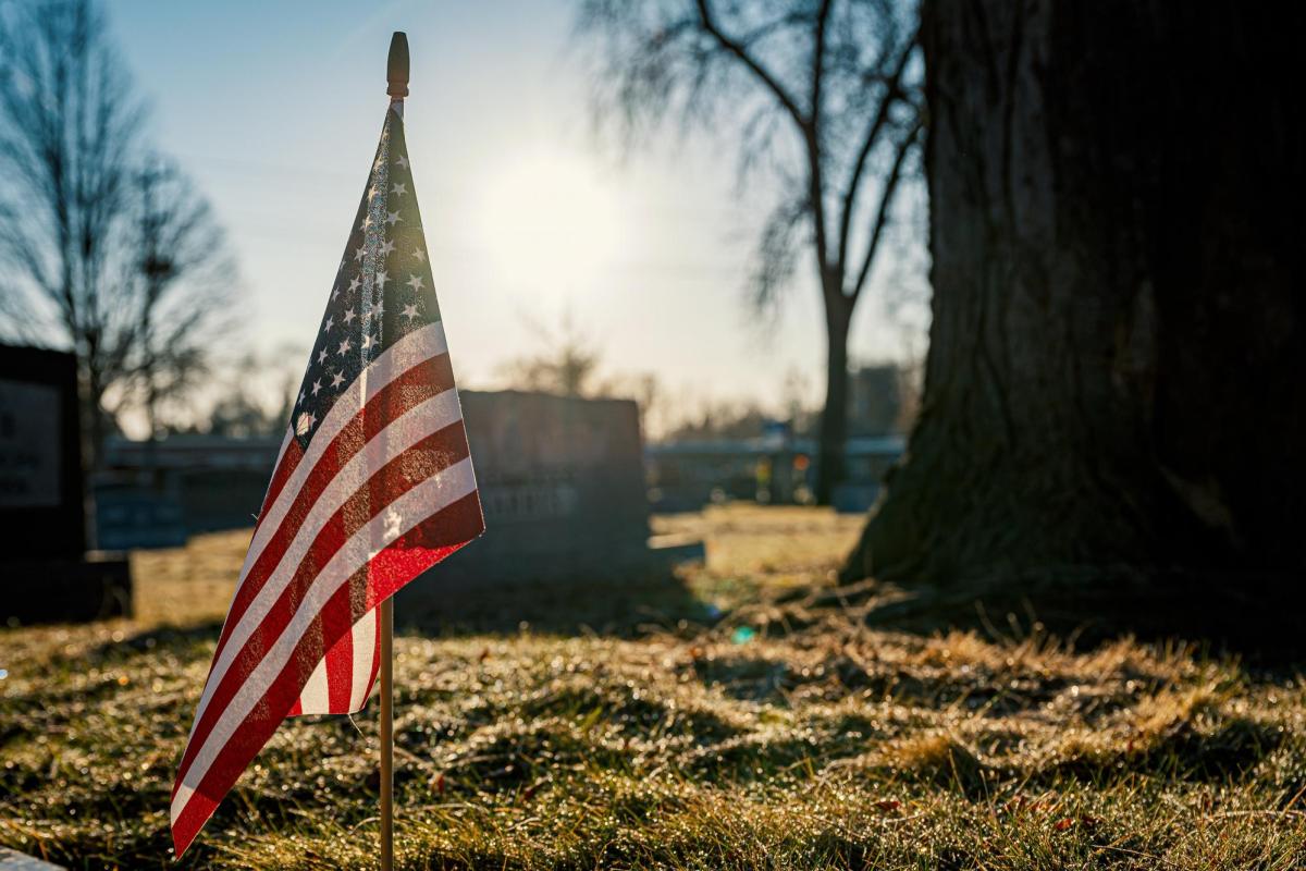 Tiny American flag in ground at cemetery