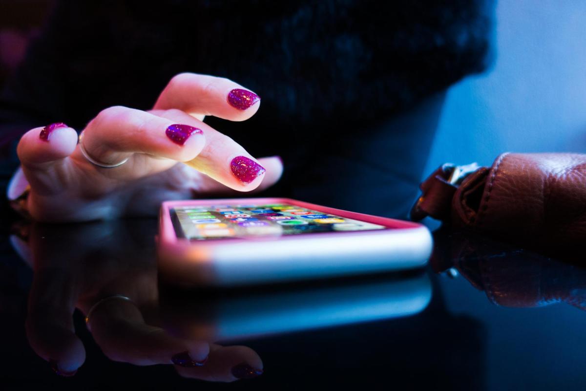 A hand hovers over a smart phone with apps