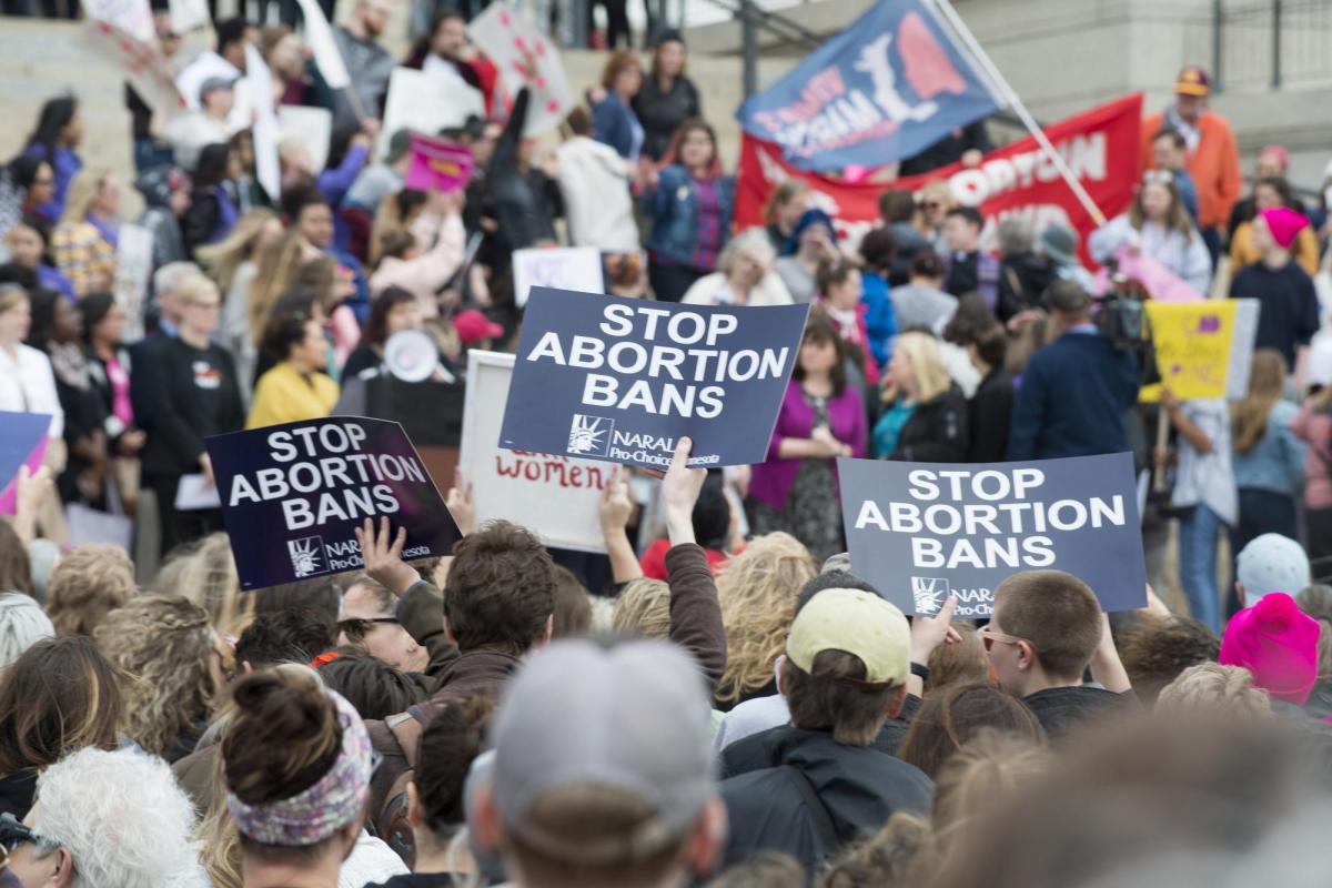 Demonstrators hold up signs at a Stop Abortion Bans rally