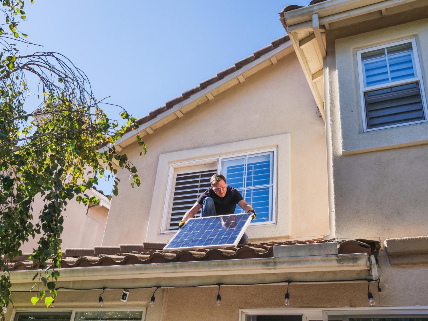 Man installing solar panels on a house