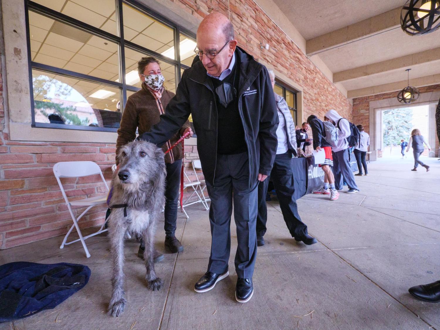 Chancellor Phil DiStefano pets a therapy dog during the Health Hut event,