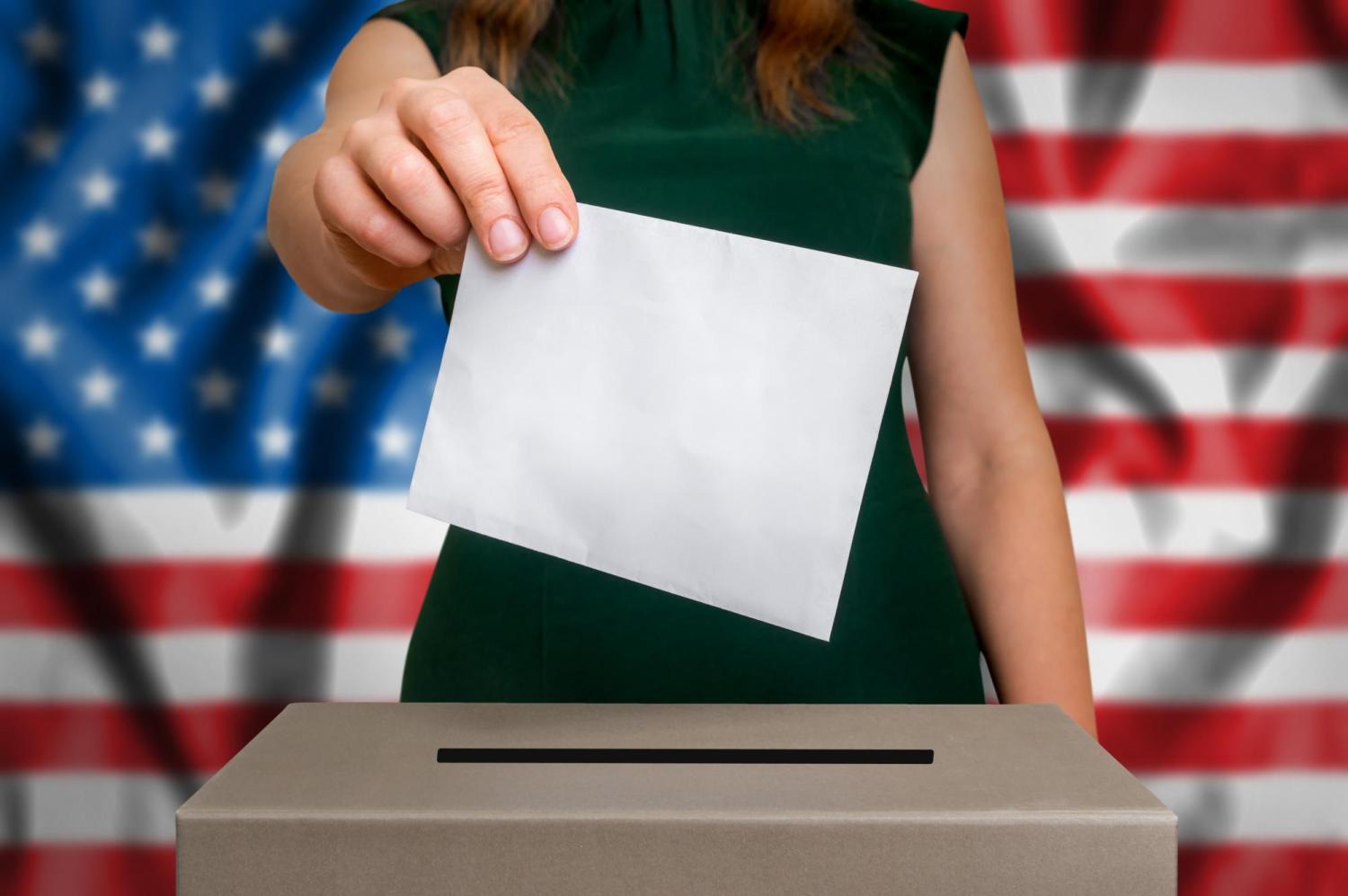 A person putting a ballot into a ballot box