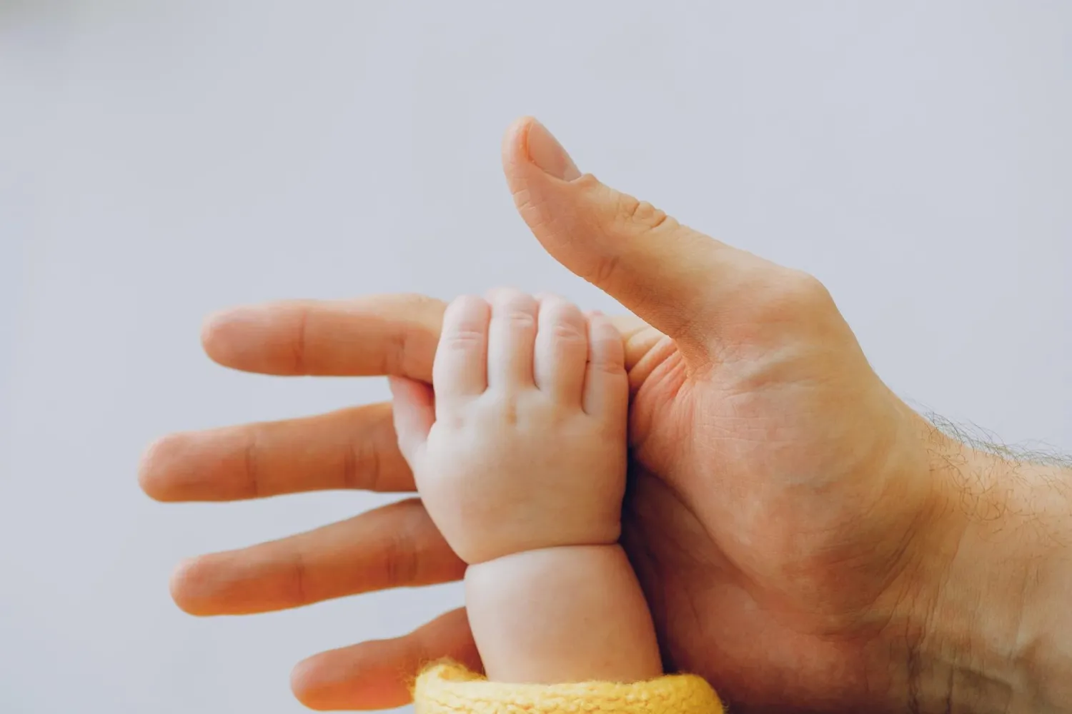 Baby holding hands with an adult