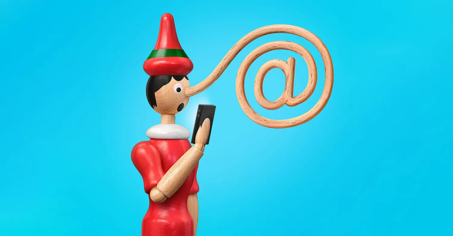 A Pinocchio doll reading a smart phone, with his elongated nose in the shape of an "@" symbol.