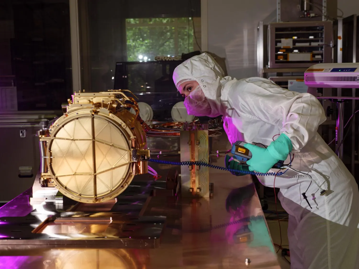 Person in protective gear inspects a scientific instrument