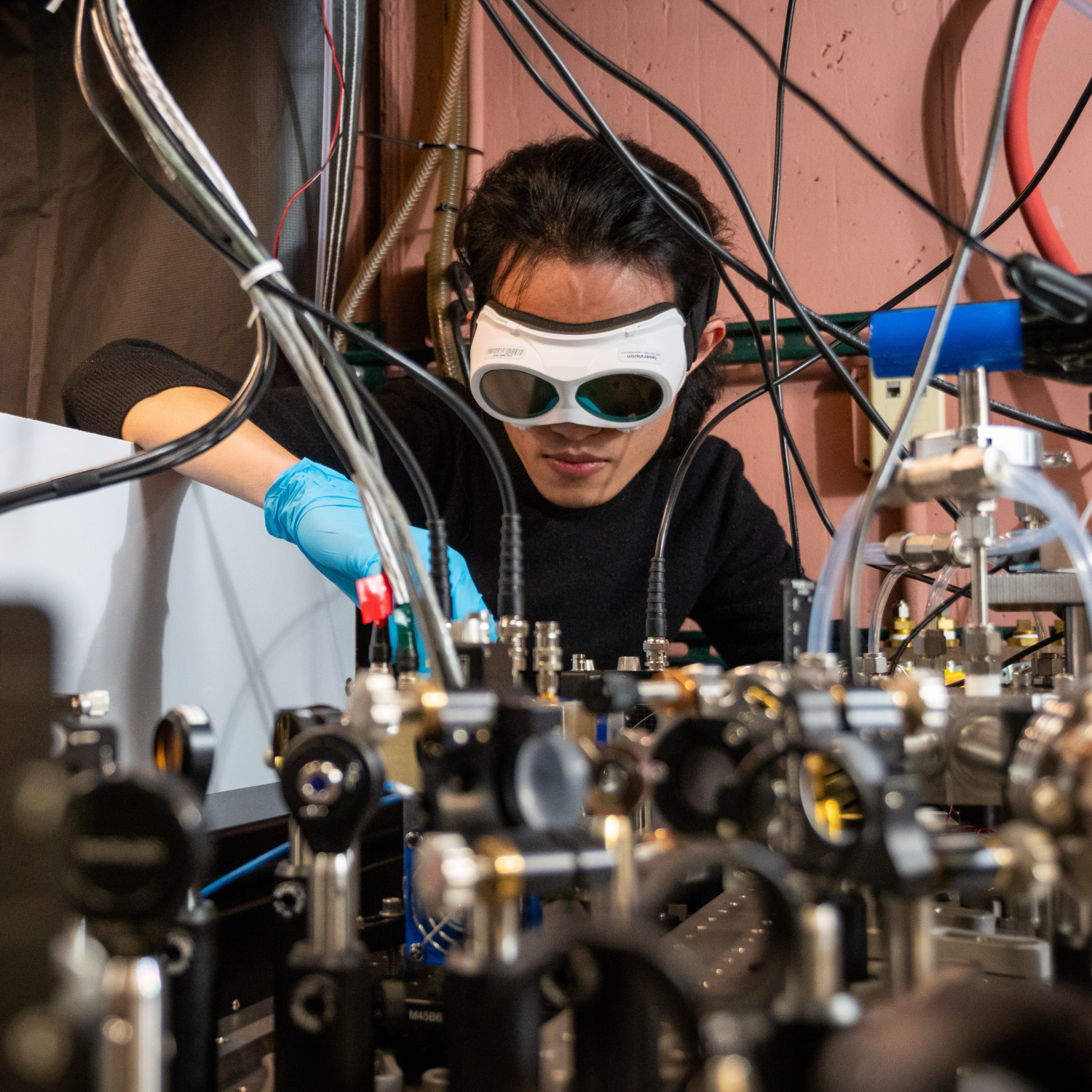 Man wearing safety goals works over scientific apparatus in a lab