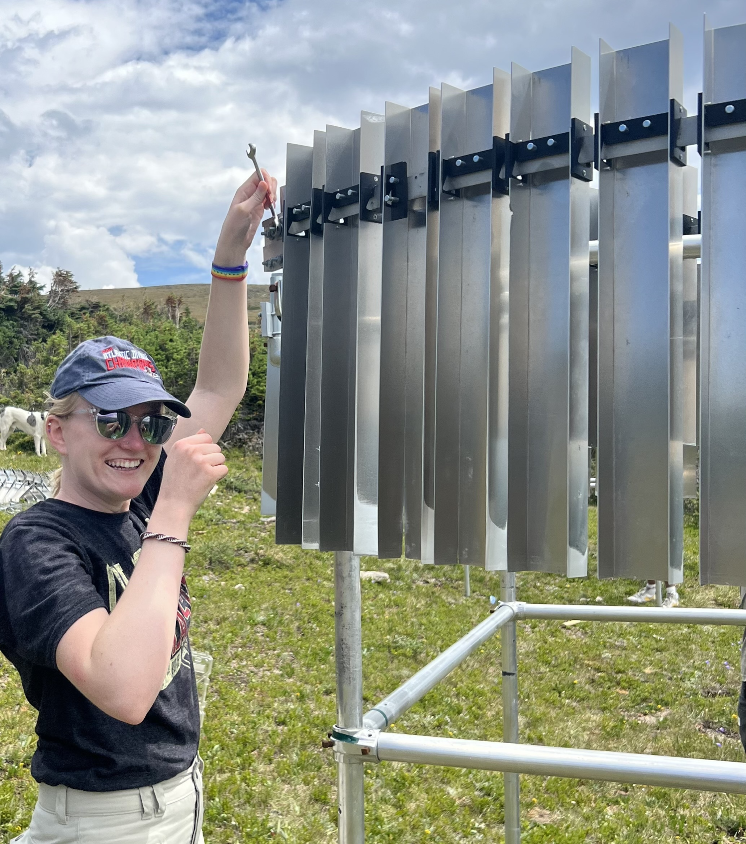 Woman standing in grassy meadow makes adjustments to metal instrument