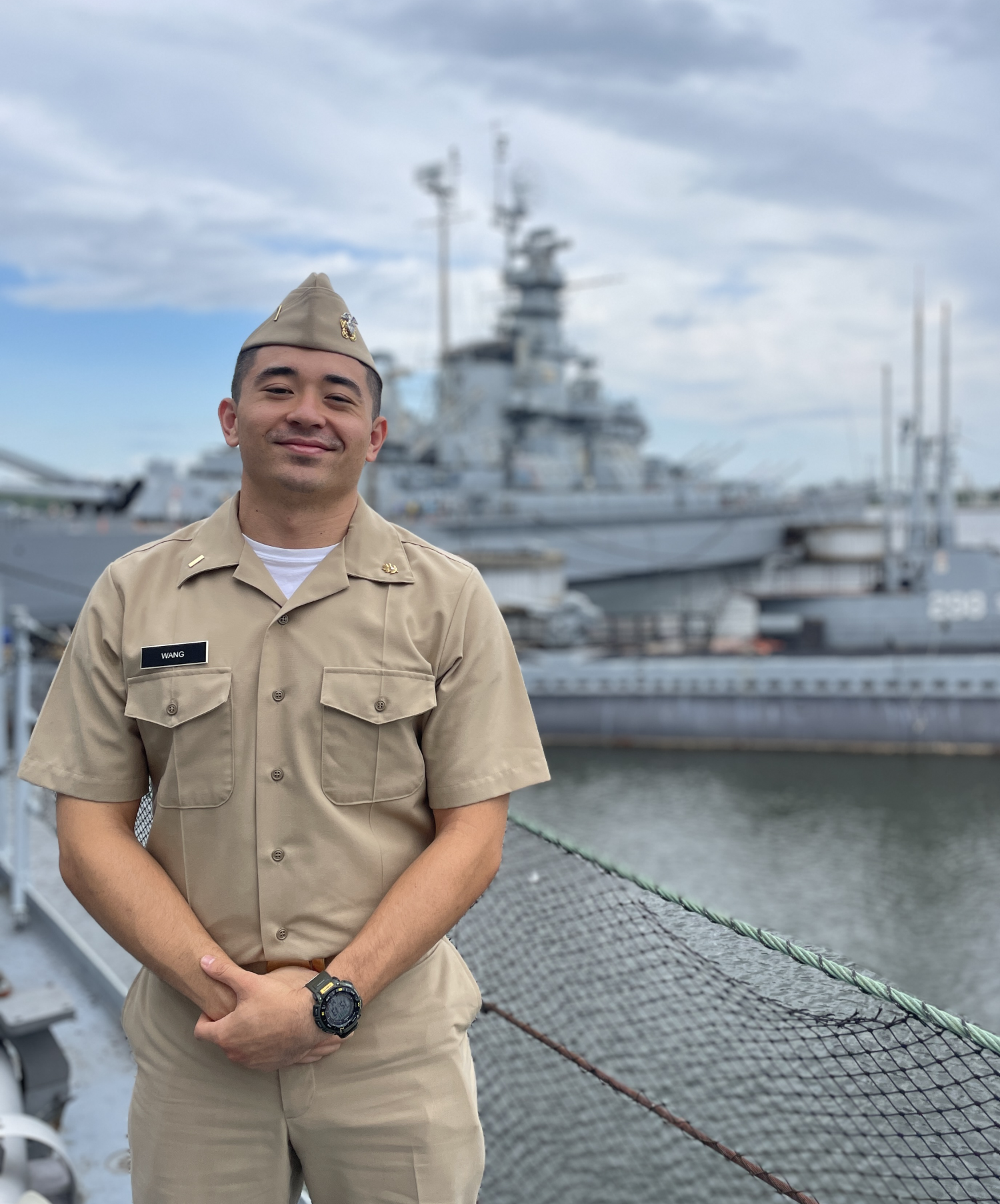 Man in naval uniform stands in front of a large vessel