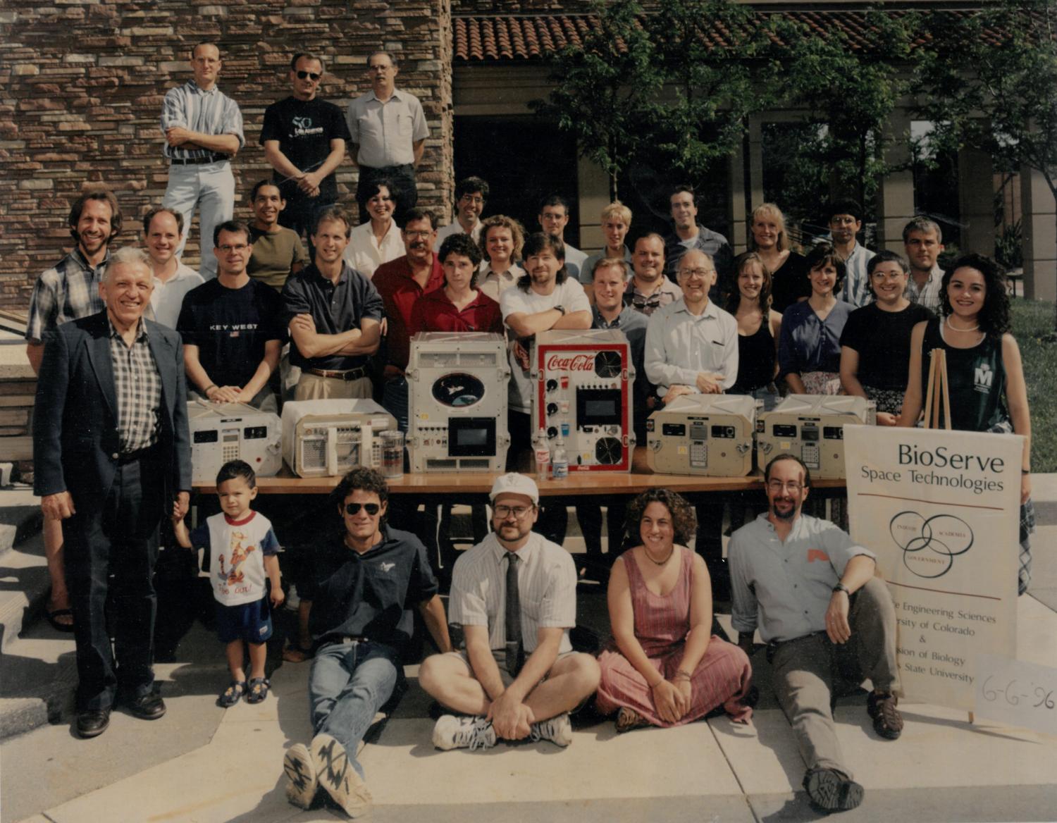 Group photo of several dozen people standing with scientific equipment