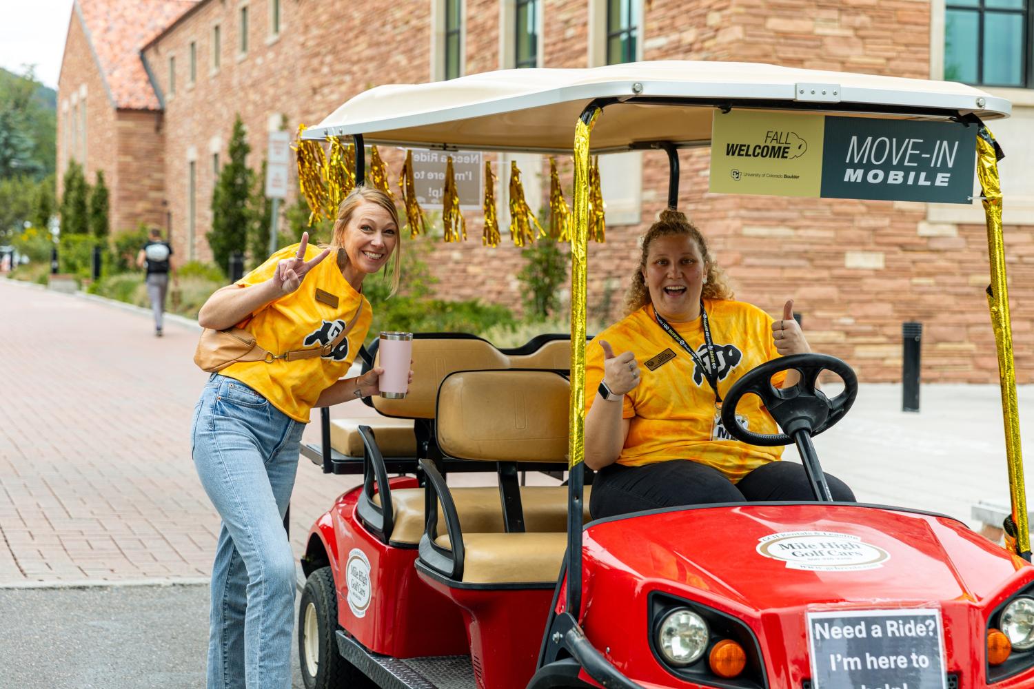 Volunteers driving a golf cart on campus during move-in