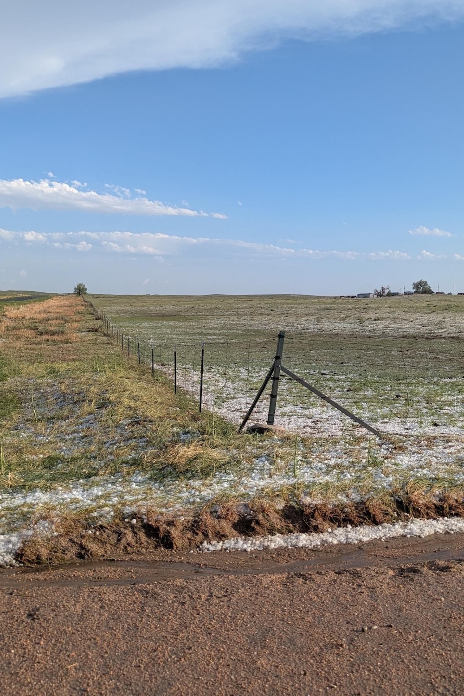 Clumps of hail next to a dirt road