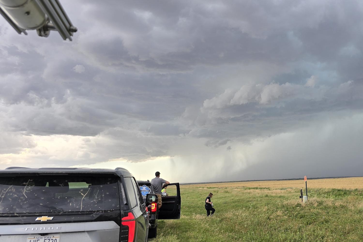 Cars on the side of the road with storm clouds overhead