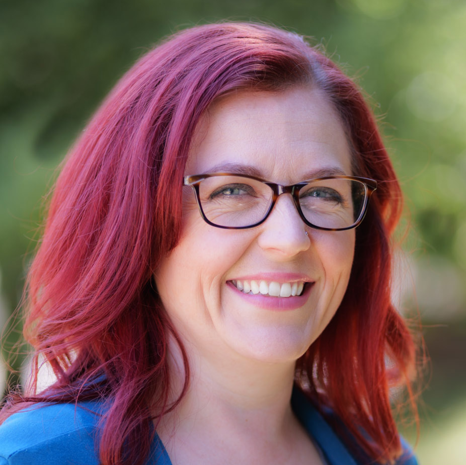 Woman with red hair and glasses poses for a portrait