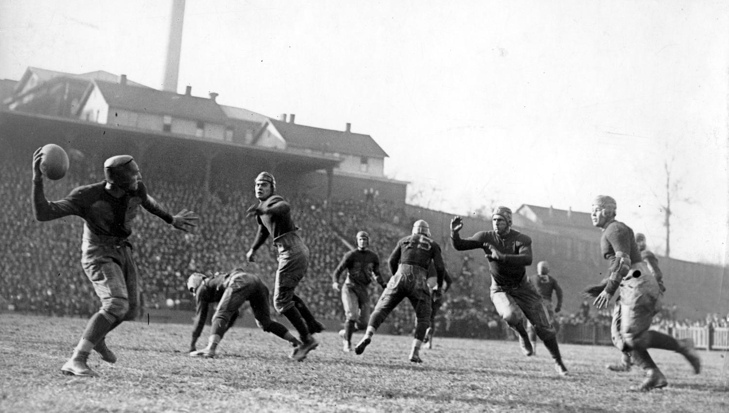 Black and white photo of men playing football in old-fashioned gear