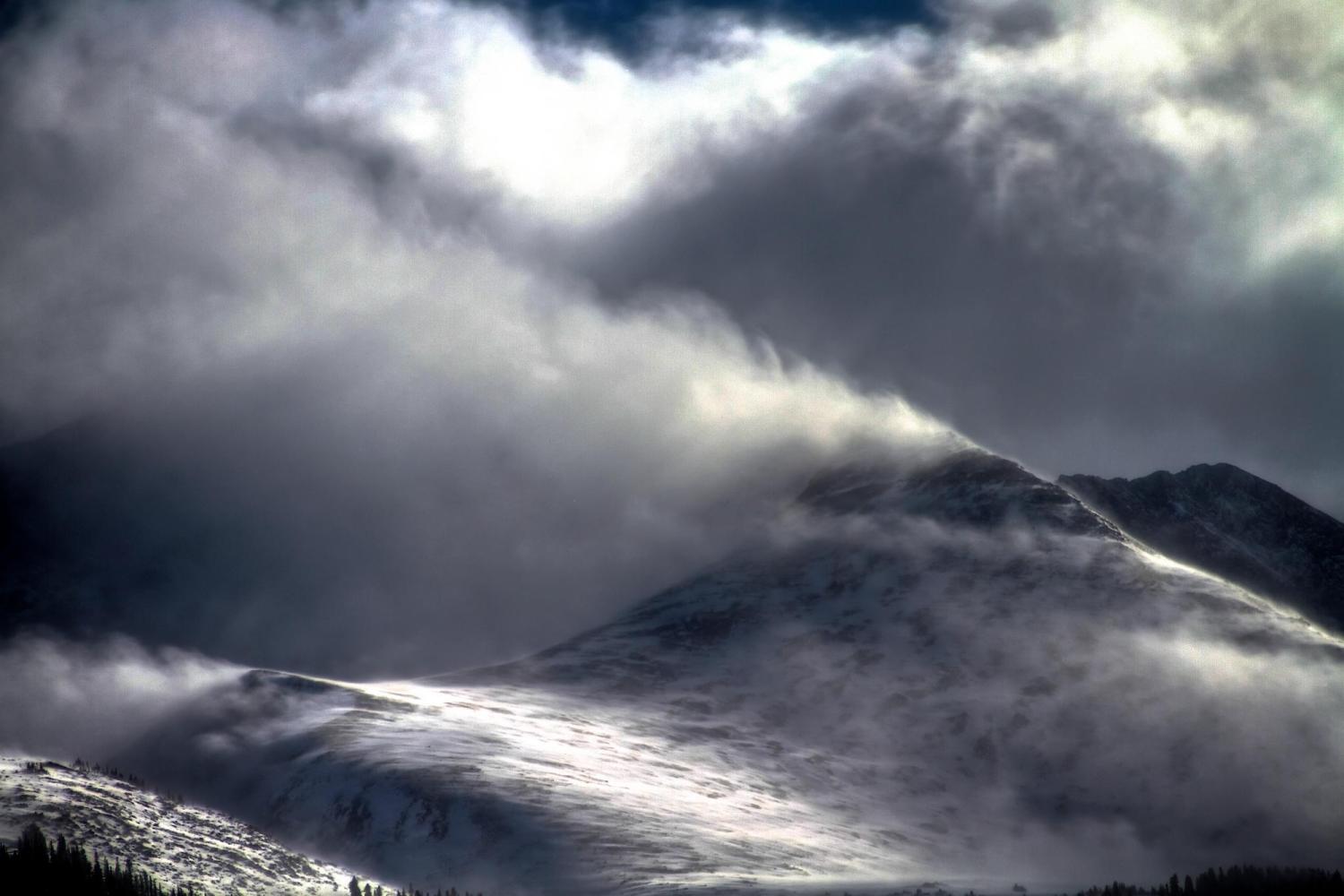 Snow flying off of a mountain top in the wind