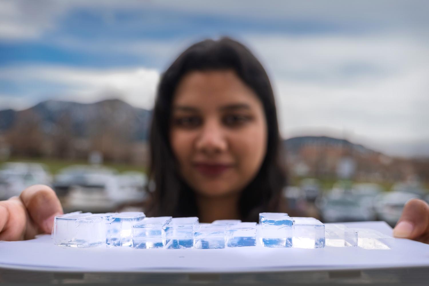A woman holds up a piece of paper with a line of clear gels on top of it