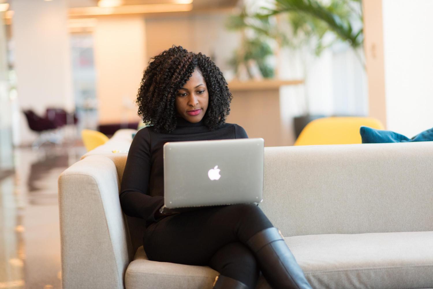 Woman on laptop sits on a couch
