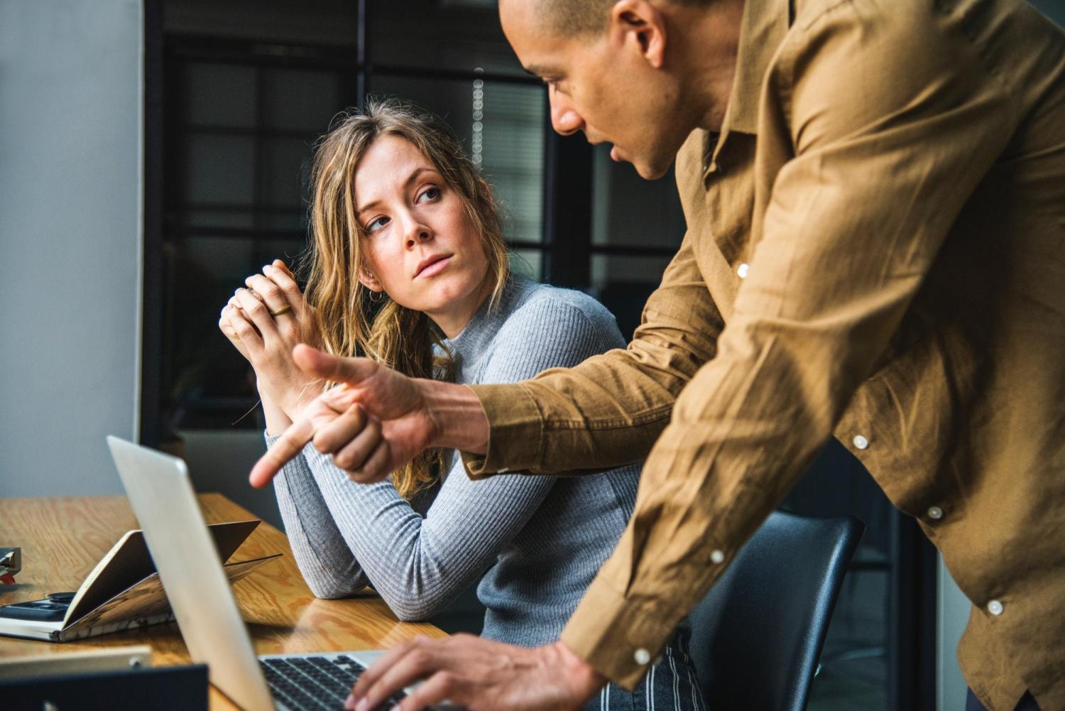Two people talking over laptop computer