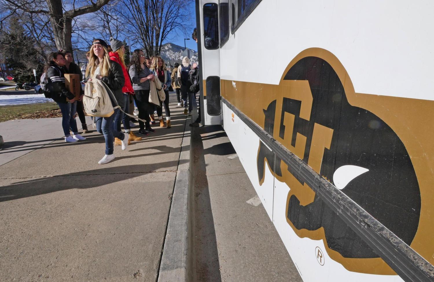 Students walk past Buff Bus