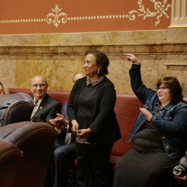 CU Boulder Professor Polly McLean stands to be recognized by state Senator Rhonda Fields after she provided a tribute of Lucille Buchanan.