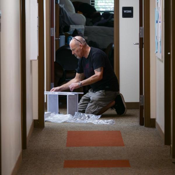 A father helps build shelves outside his daughter’s dorm room in Baker Hall on Tuesday, Aug. 17, 2021. (Photo by Glenn Asakawa/University of Colorado)