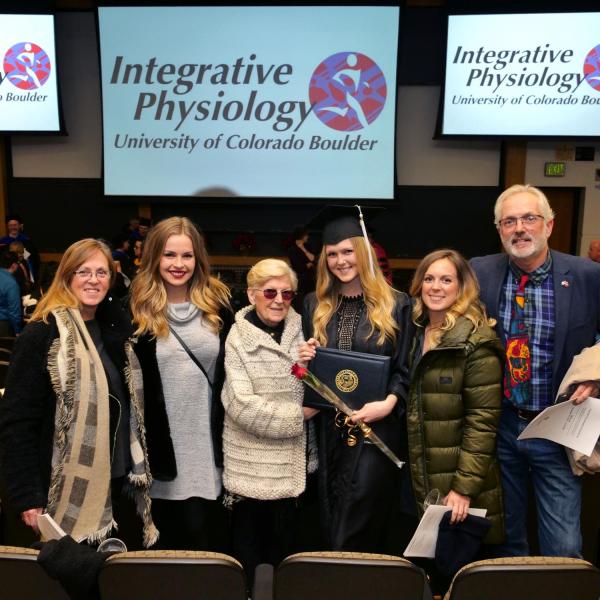 Graduate poses with family for photo after Integrative Physiology recognition ceremony