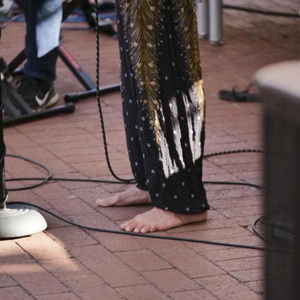 Musician rocks bare feet while singing and playing guitar on Pearl Street