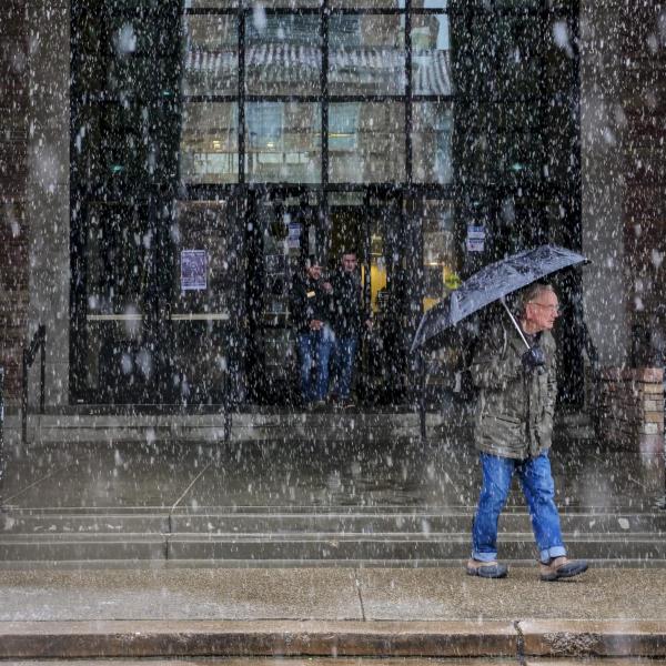 A person ventures out into snowfall with an umbrella. Photo by Patrick Campbell.
