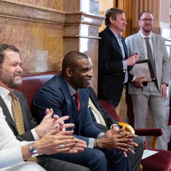 Deion Sanders sits between CU President Todd Saliman, left, and CU Boulder Chancellor Phil DiStefano, while being honored in the Senate Chamber