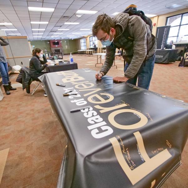 Students sign the Class of 2021 banner and pick up regalia at the 2021 Gear Grab event. (Photo by Casey Cass/University of Colorado)