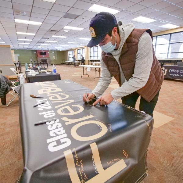 Students sign the Class of 2021 banner and pick up regalia at the 2021 Gear Grab event. (Photo by Casey Cass/University of Colorado)