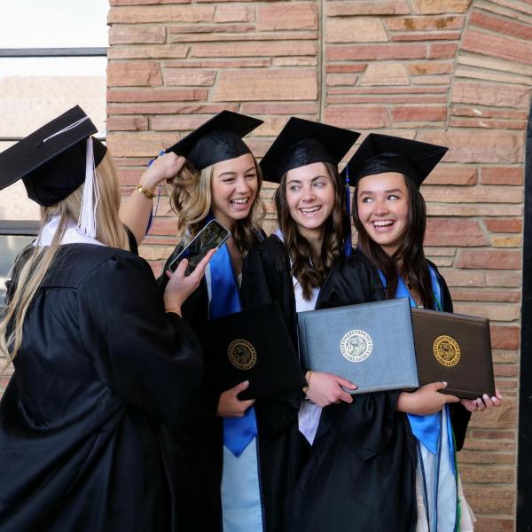 Accounting graduate Alexa Reber, second from left, political science and anthropology graduate Katie Burns, second from right, and finance graduate Claudia Hall, right, pose for a friend’s photo during CU Boulder’s Graduate Appreciation Days events. (Photo by Glenn Asakawa/University of Colorado)